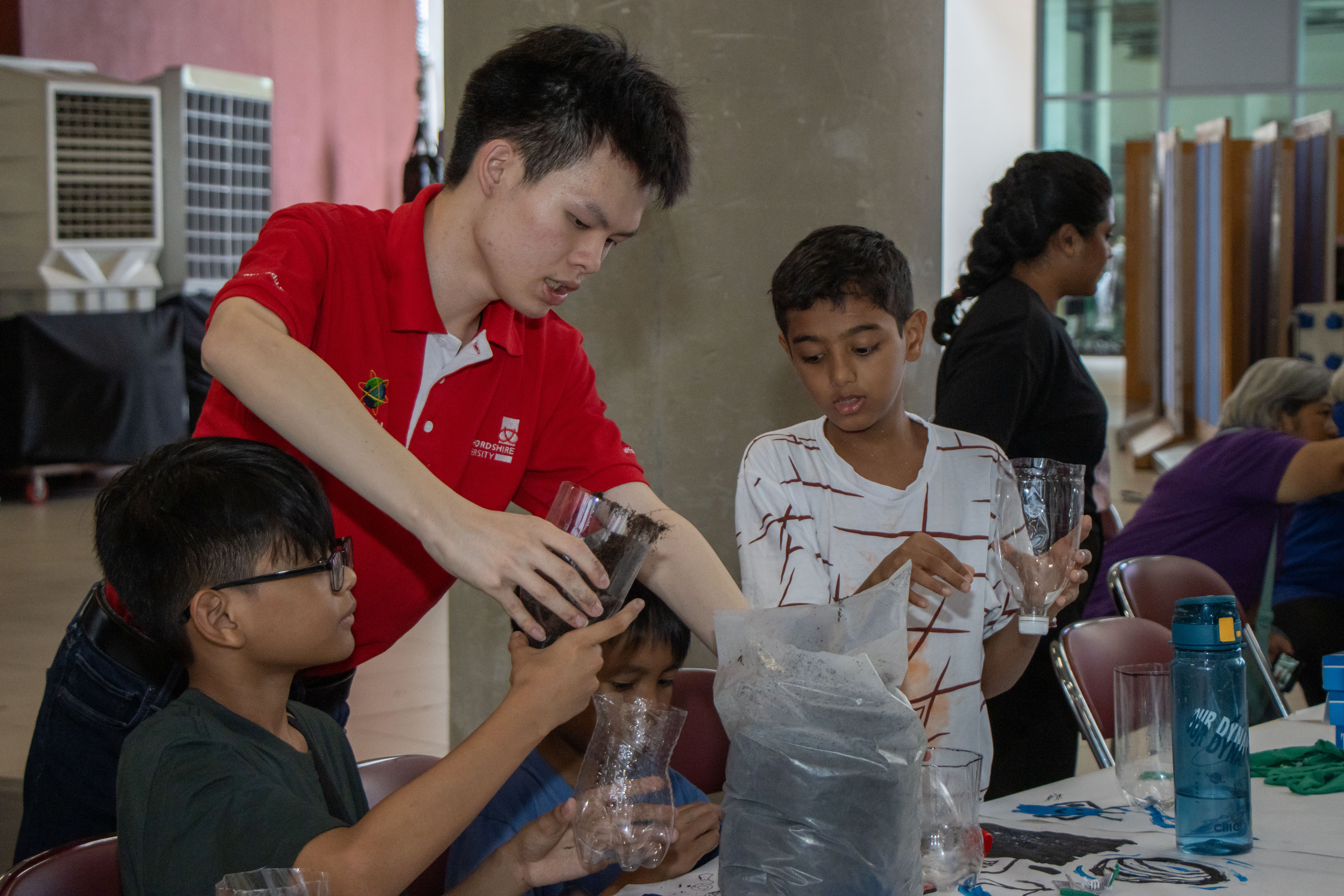 Children learning to create their own terrariums using soil, plants, and decorative elements during a hands-on workshop